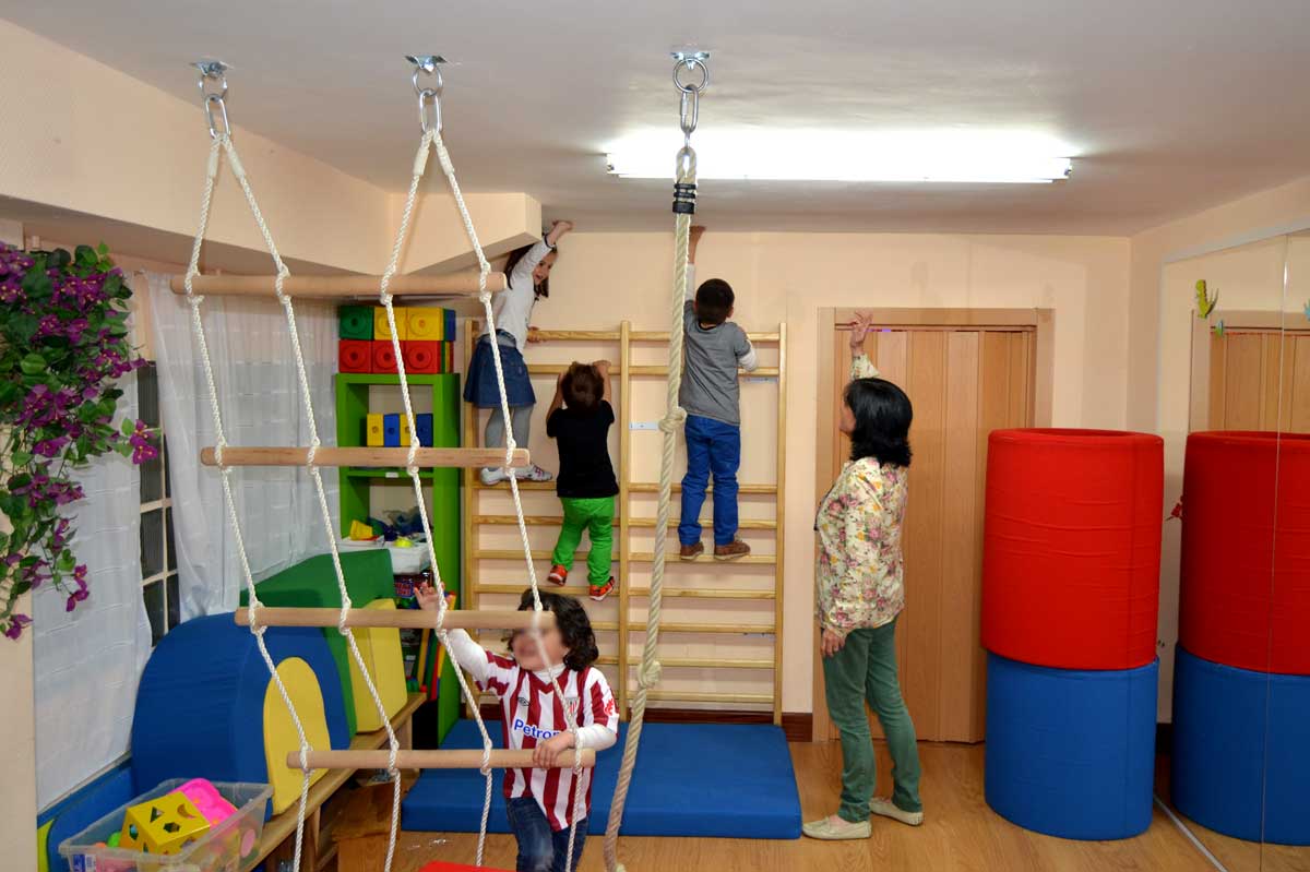 Varios niños y niñas juegan en una sala de psicomotricidad de Zubikoa con una monitora