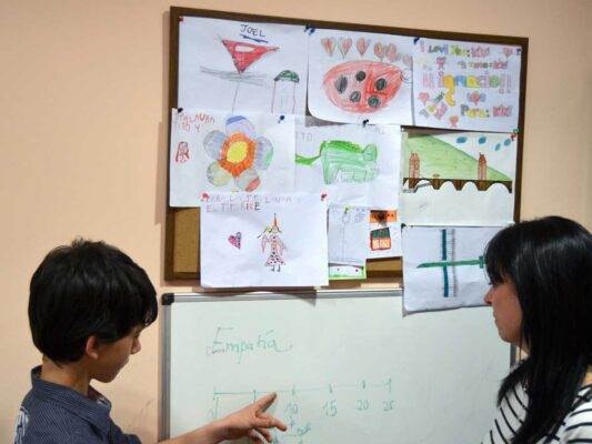 Una psicologa atiende a un niño frente a una pizarra