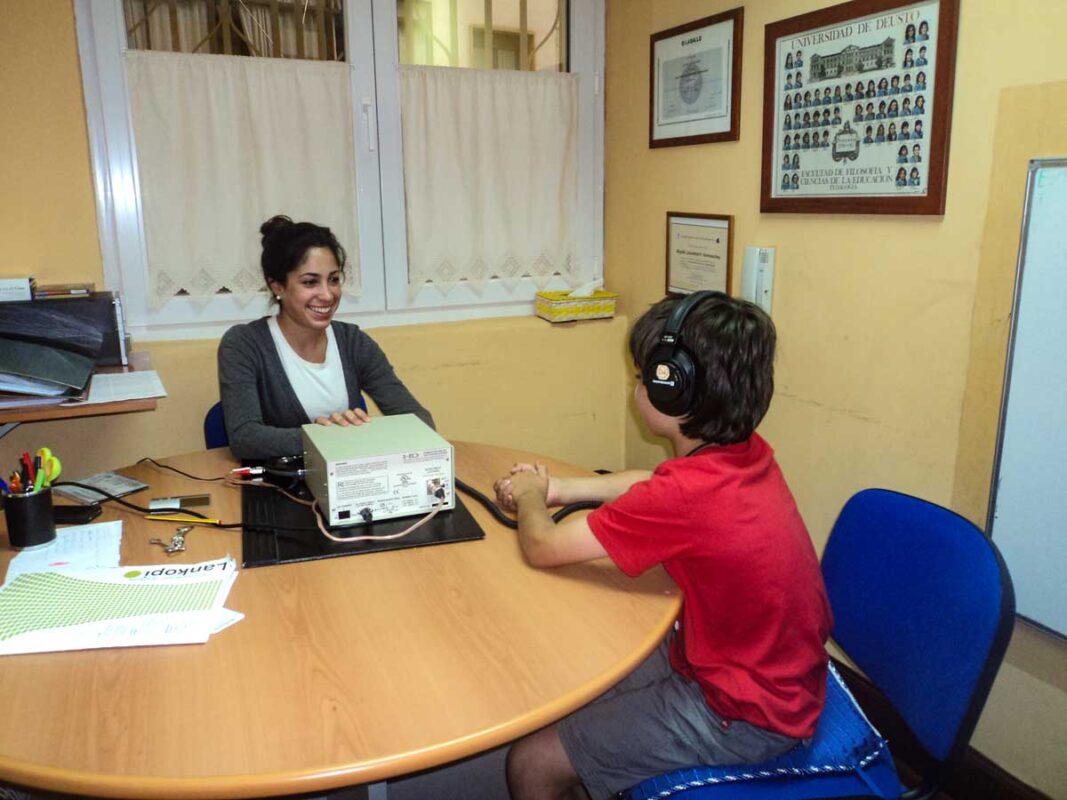 Una trabajadora de Zubikoa atiende a un niño con auriculares